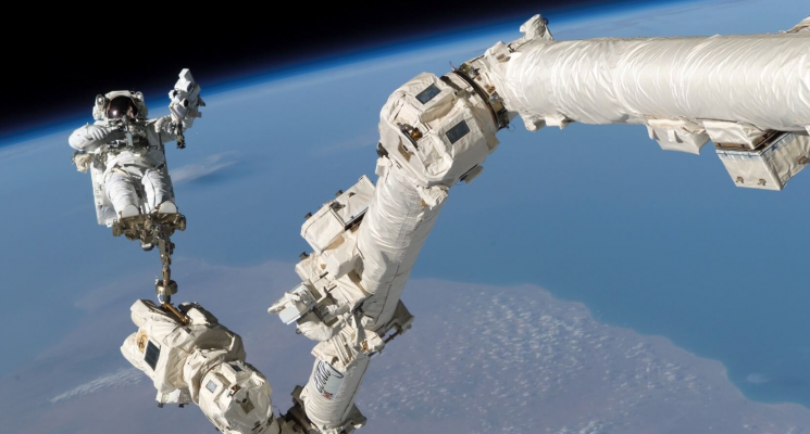 Канадские технологии в космосе. Роботизированная рука Canadarm2 и космонавт. Фото.