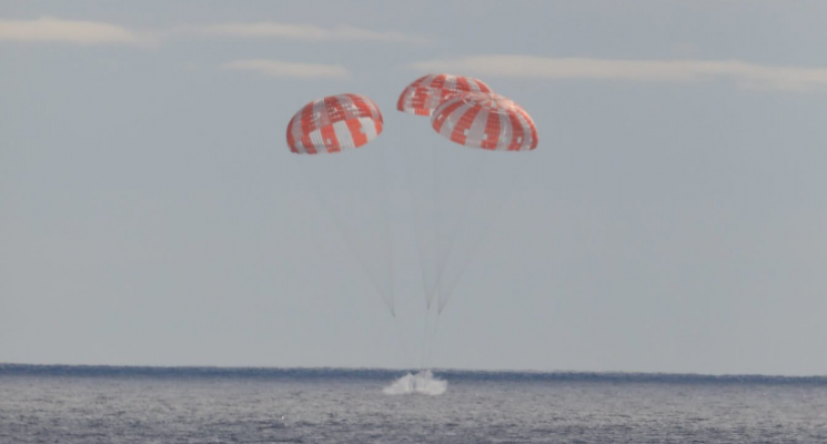 Возвращение корабля «Орион» на Землю. Космический корабль «Орион» опускается на воду при помощи трех парашютов. Фото.